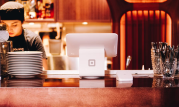 a member of kitchen staff behind a counter with an electronic order system to show common reasons restaurants are not making profits