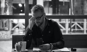 man sat in a cafe on his phone looking at how a consultancy service can help his start-up restaurant