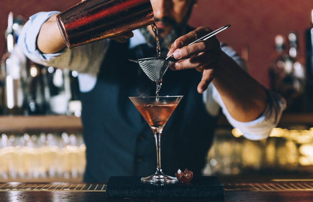 Pouring a cocktail carefully after learning how to make a bar profitable using correct measurements